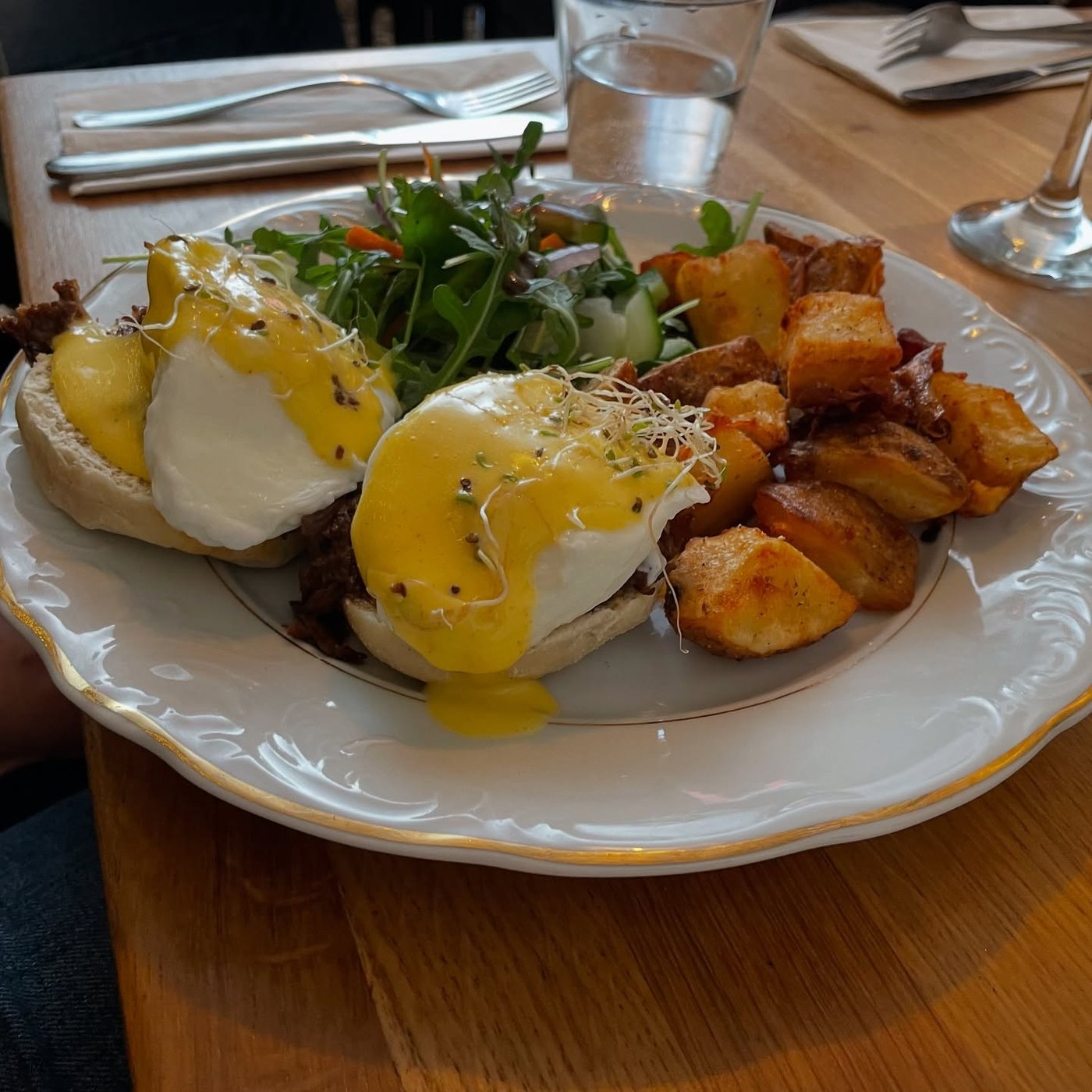 Eggs Benedict plate with potatoes and greens